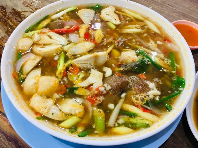 ต้มยำขาหมูชามใหญ่ น้ำซุปสีส้ม มีพริกและสมุนไพร