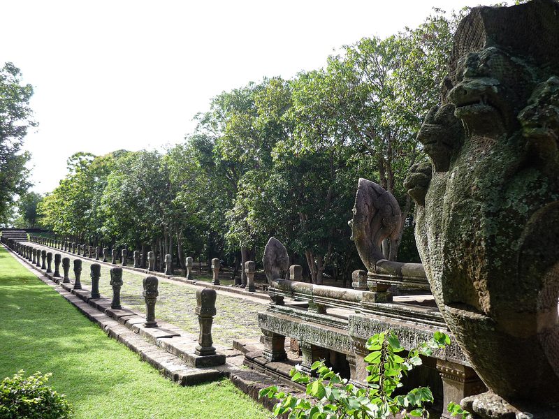 ราวนาคหินทรายเรียงยาวขนาบทางเดินขึ้นปราสาท มีสนามหญ้าและต้นไม้รอบ ๆ